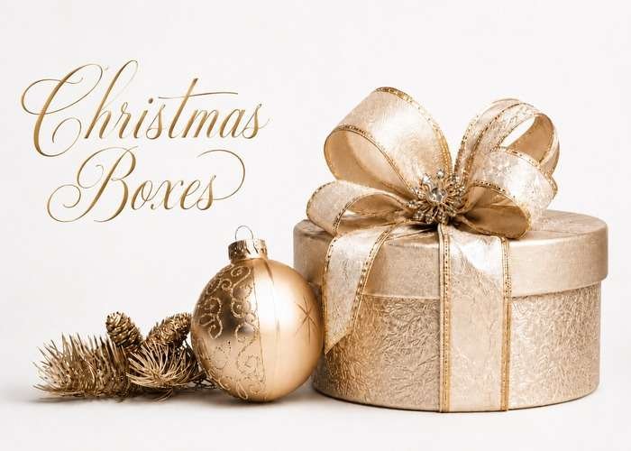 Round gold Christmas gift box with a large ribbon bow, gold ornament, and pinecones on a white background.
