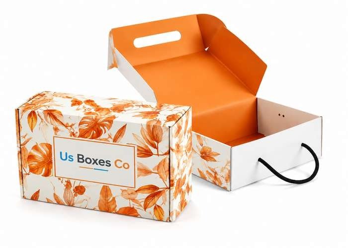 Two die cut boxes with orange floral designs and handles, one open showing the orange interior, the other closed with "Us Boxes Co" logo.